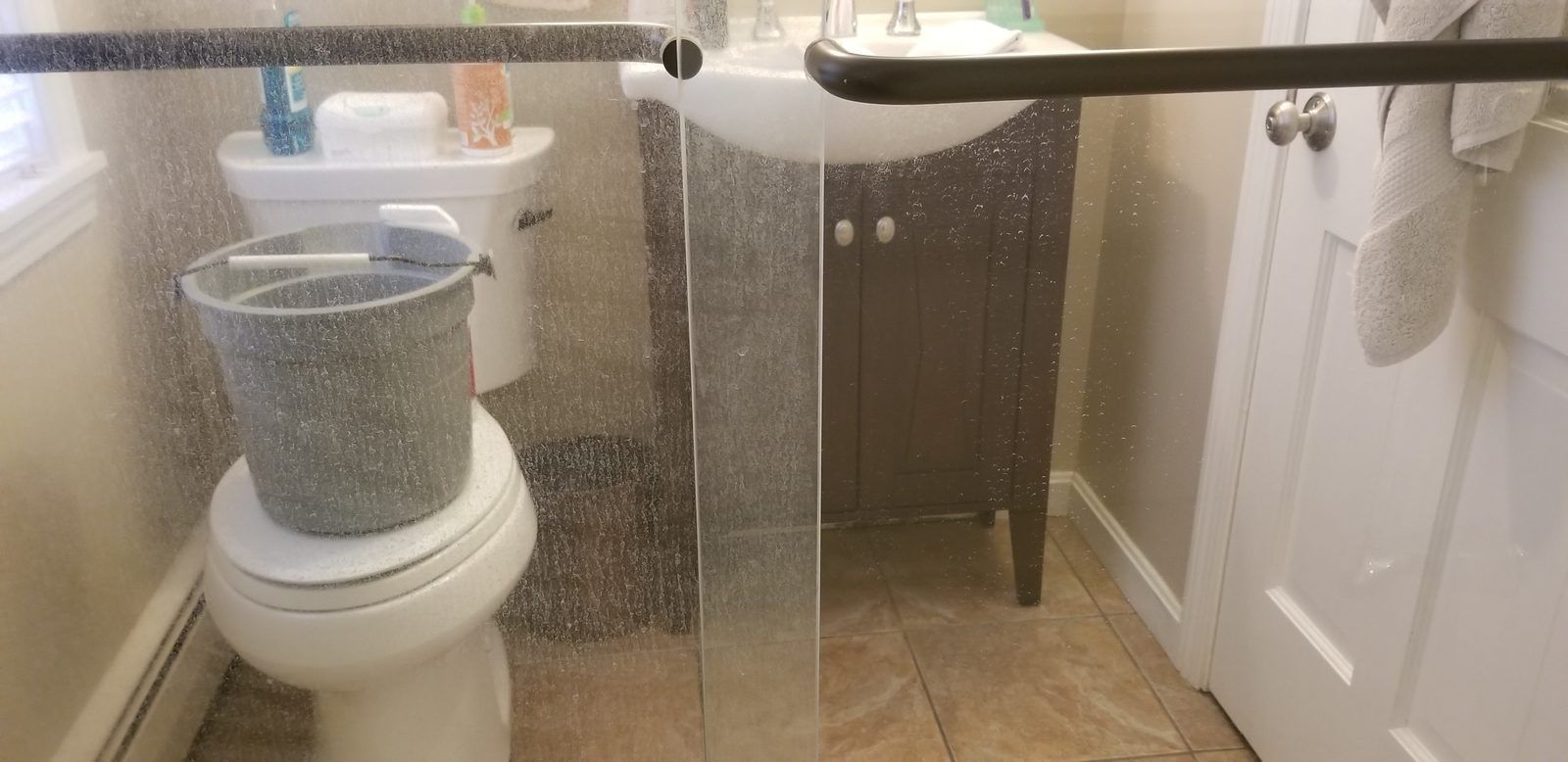 Shower door covered in heavy hard water spots before cleaning, Ipswich MA