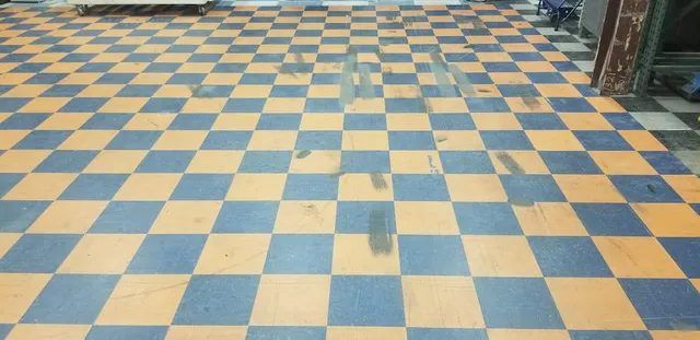 Commercial VCT floor in Waltham, MA with black forklift tire marks and a dull finish before cleaning