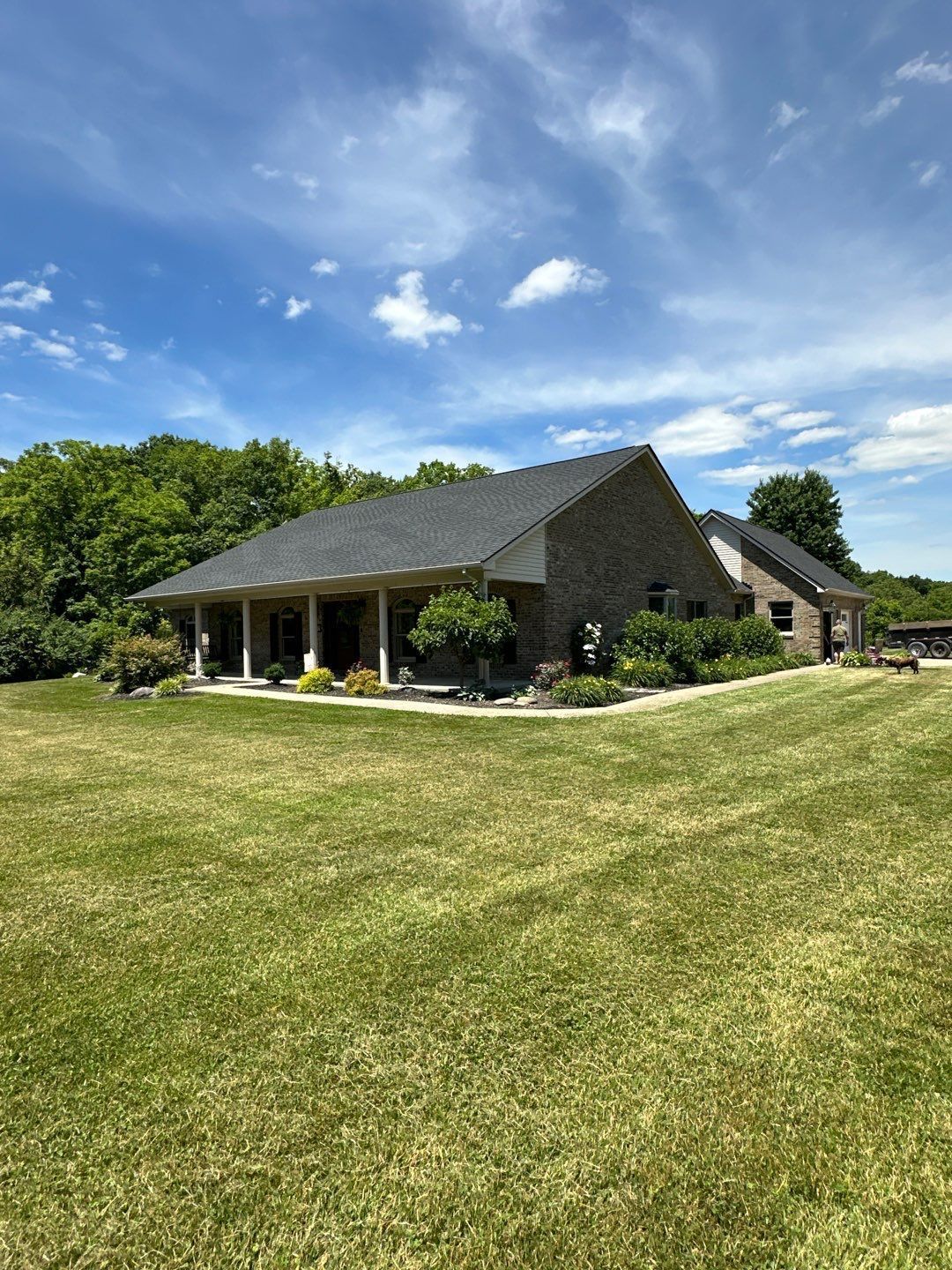 Brick suburban house with gray roof, front lawn, and a basketball hoop by the driveway