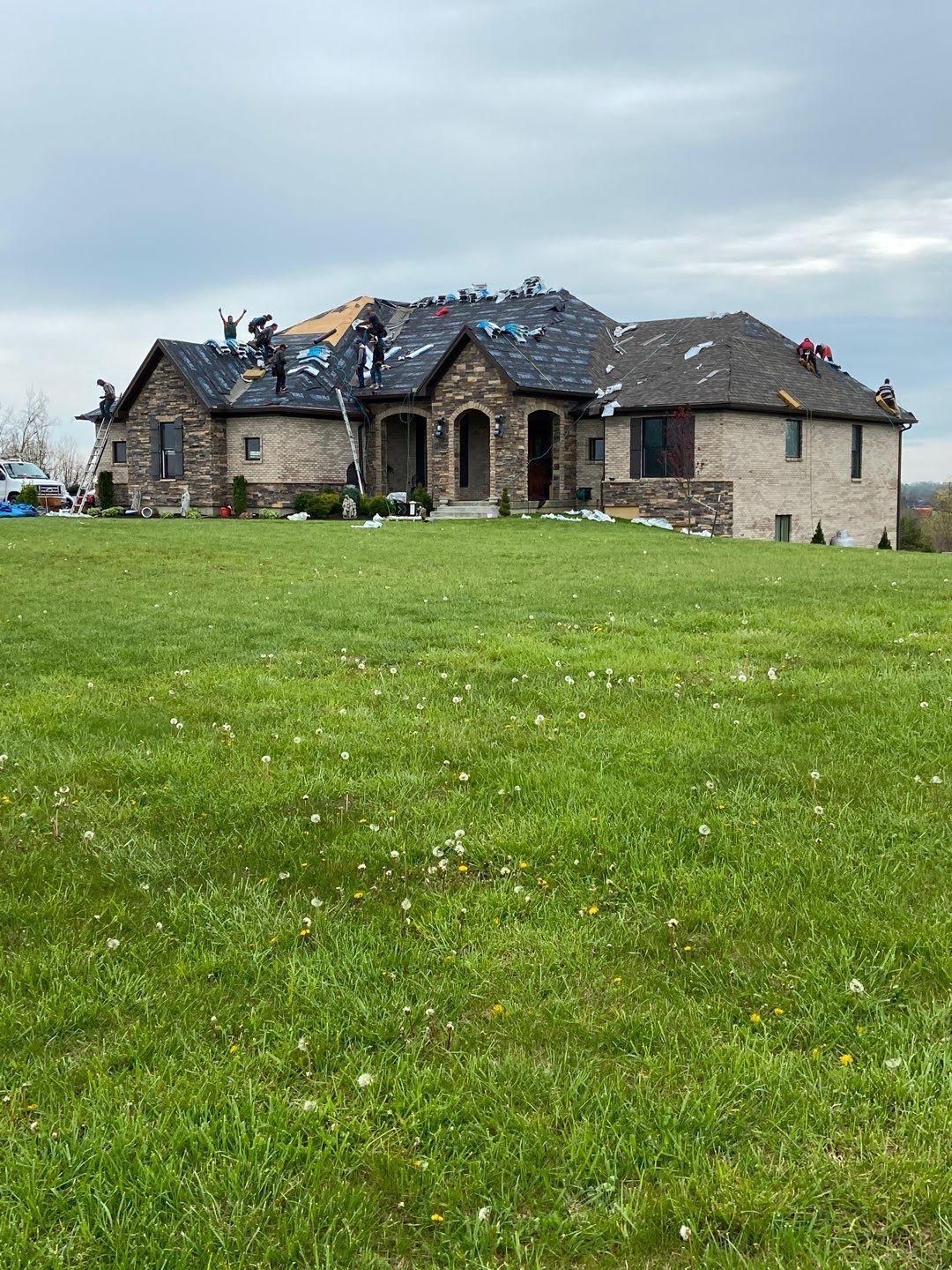 A damaged stone house with a collapsed roof in a grassy field under a cloudy sky