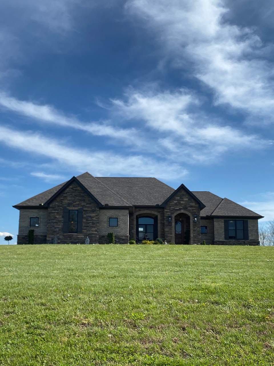 Stone house on a grassy hill under a blue, cloud-streaked sky.