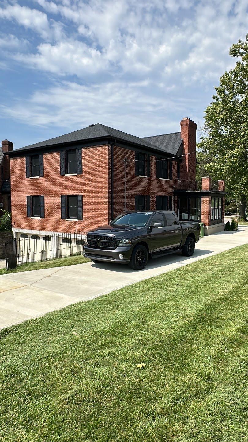 Brick two-story house with black SUV parked in the driveway on a sunny day