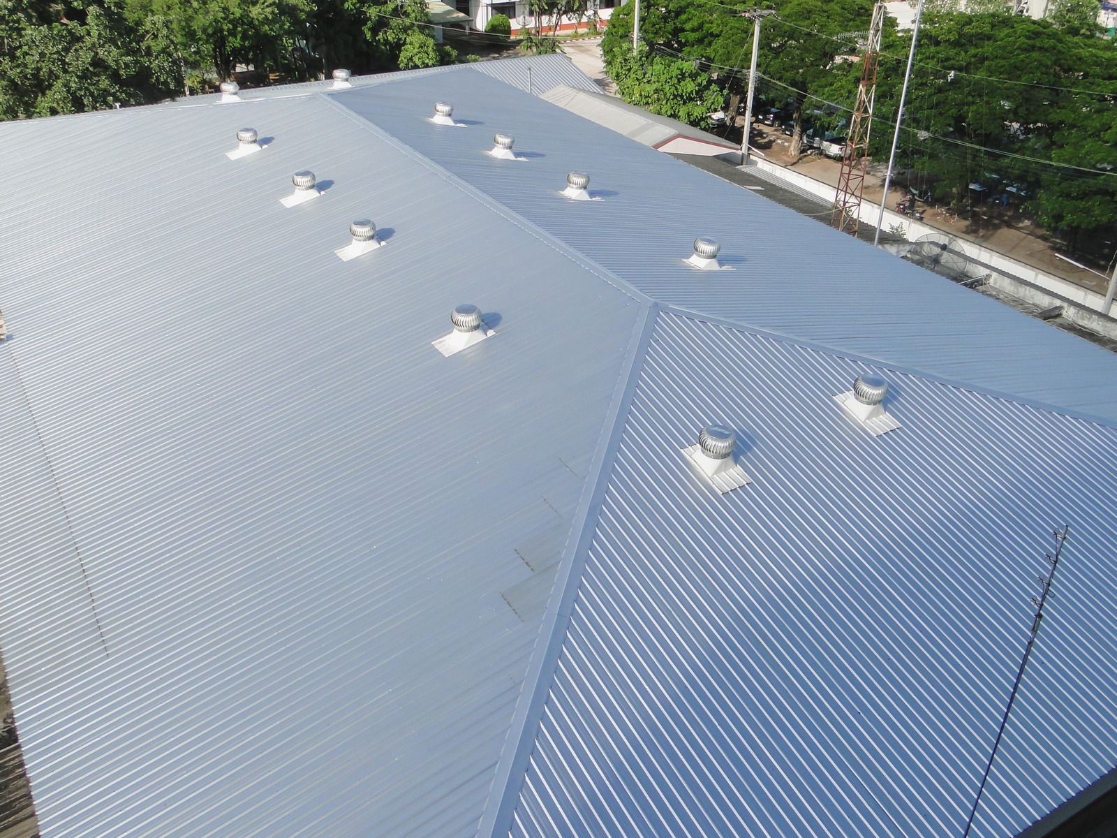 Blue metal roof with multiple vents and skylights, viewed from above