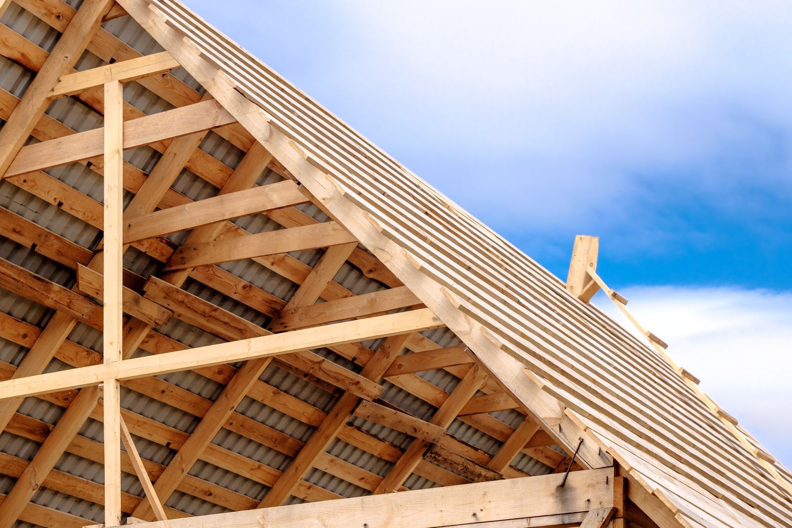 Wooden roof trusses under construction against a blue sky