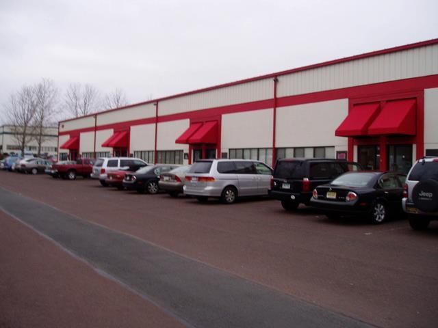 Warehouse exterior with red trim and awnings; cars parked in front