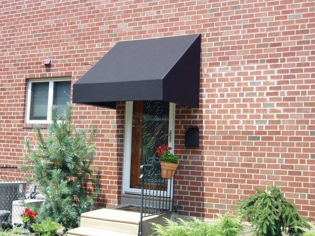 Black awning over a front door on a brick building; plants, steps