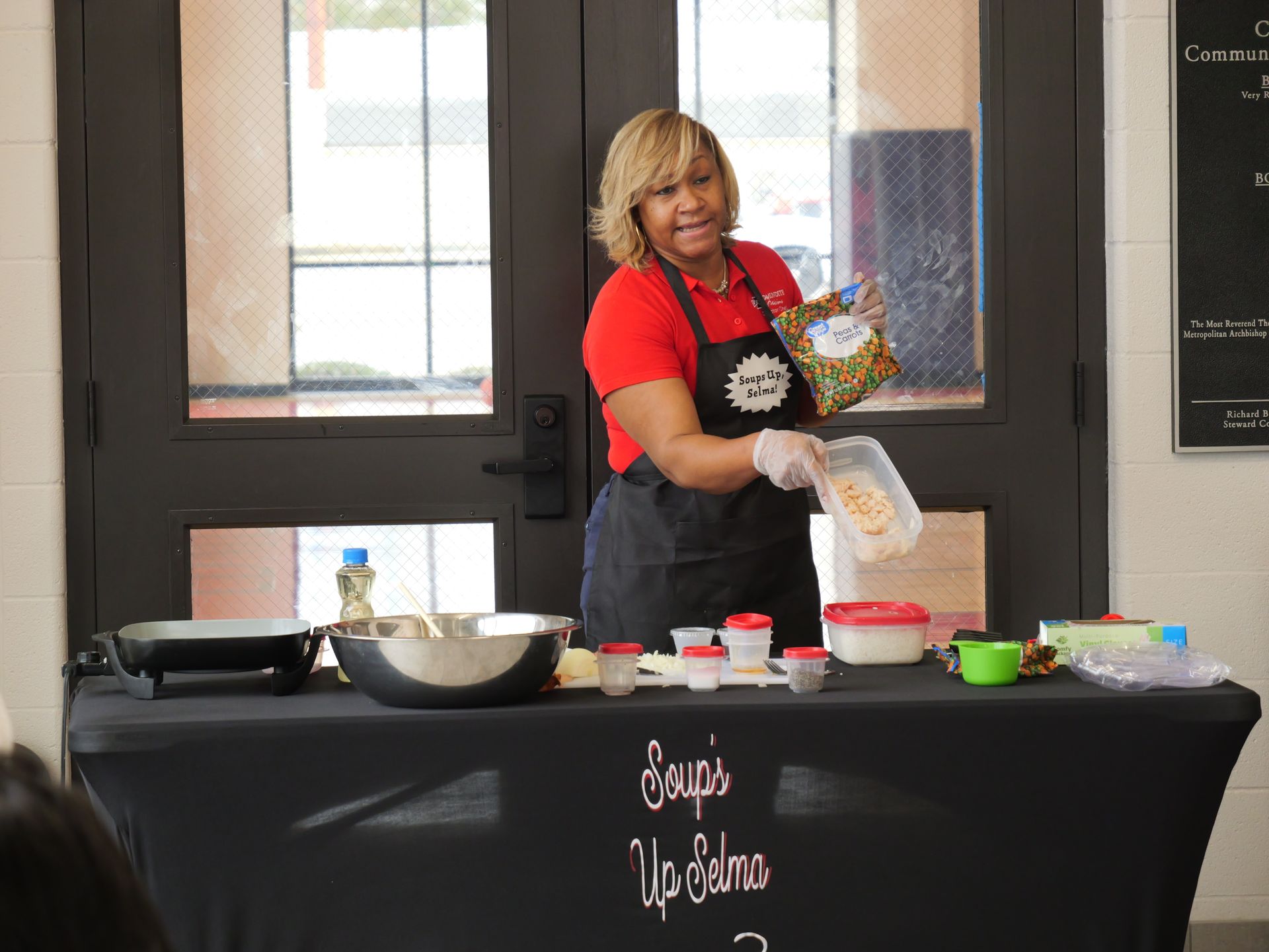 A woman is standing in front of a table holding a bag of food.