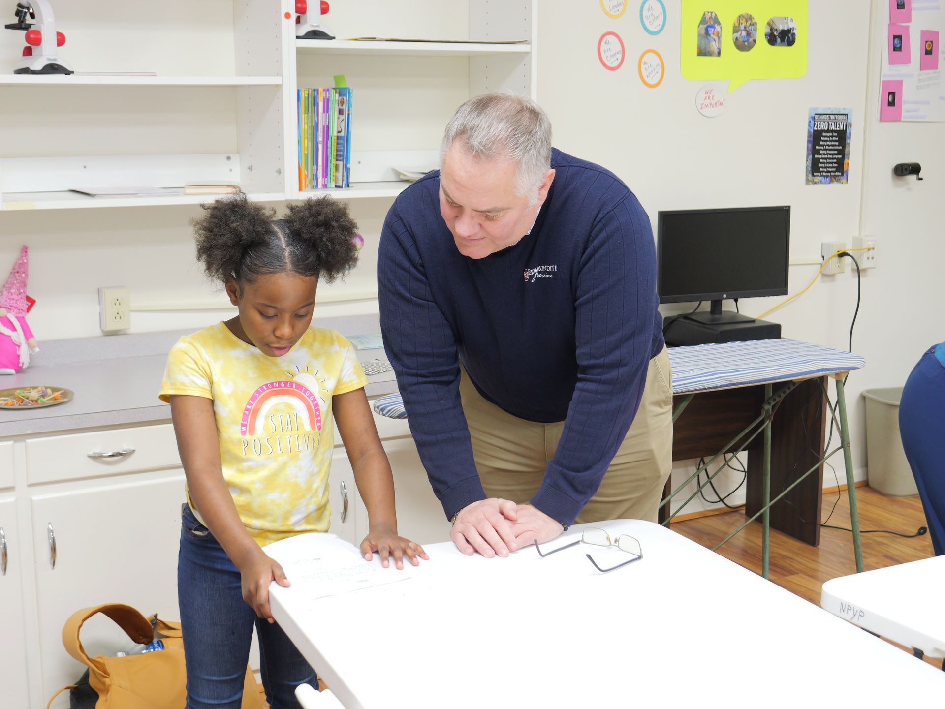 A man and a little girl are standing next to a table.