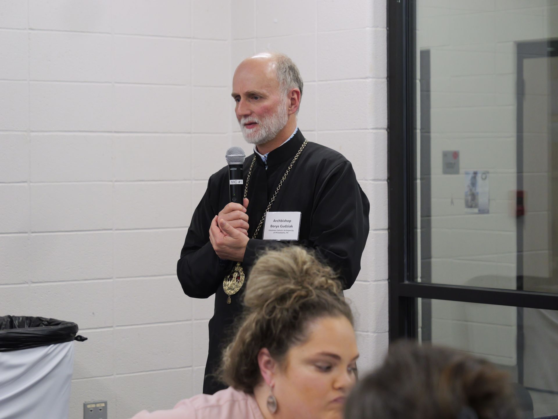 A man with a beard is holding a microphone in front of a group of people.