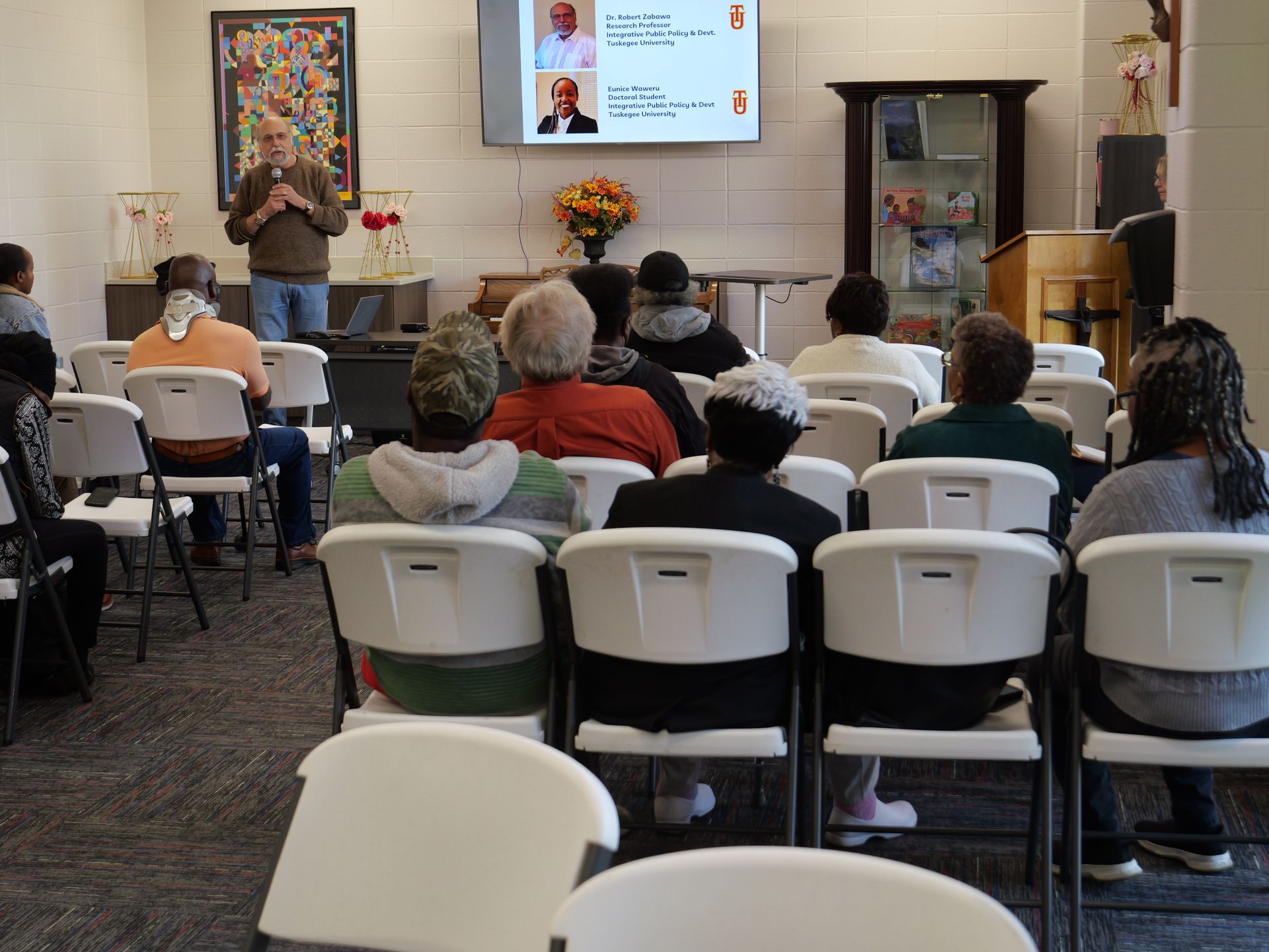 A group of people are sitting in chairs watching a presentation