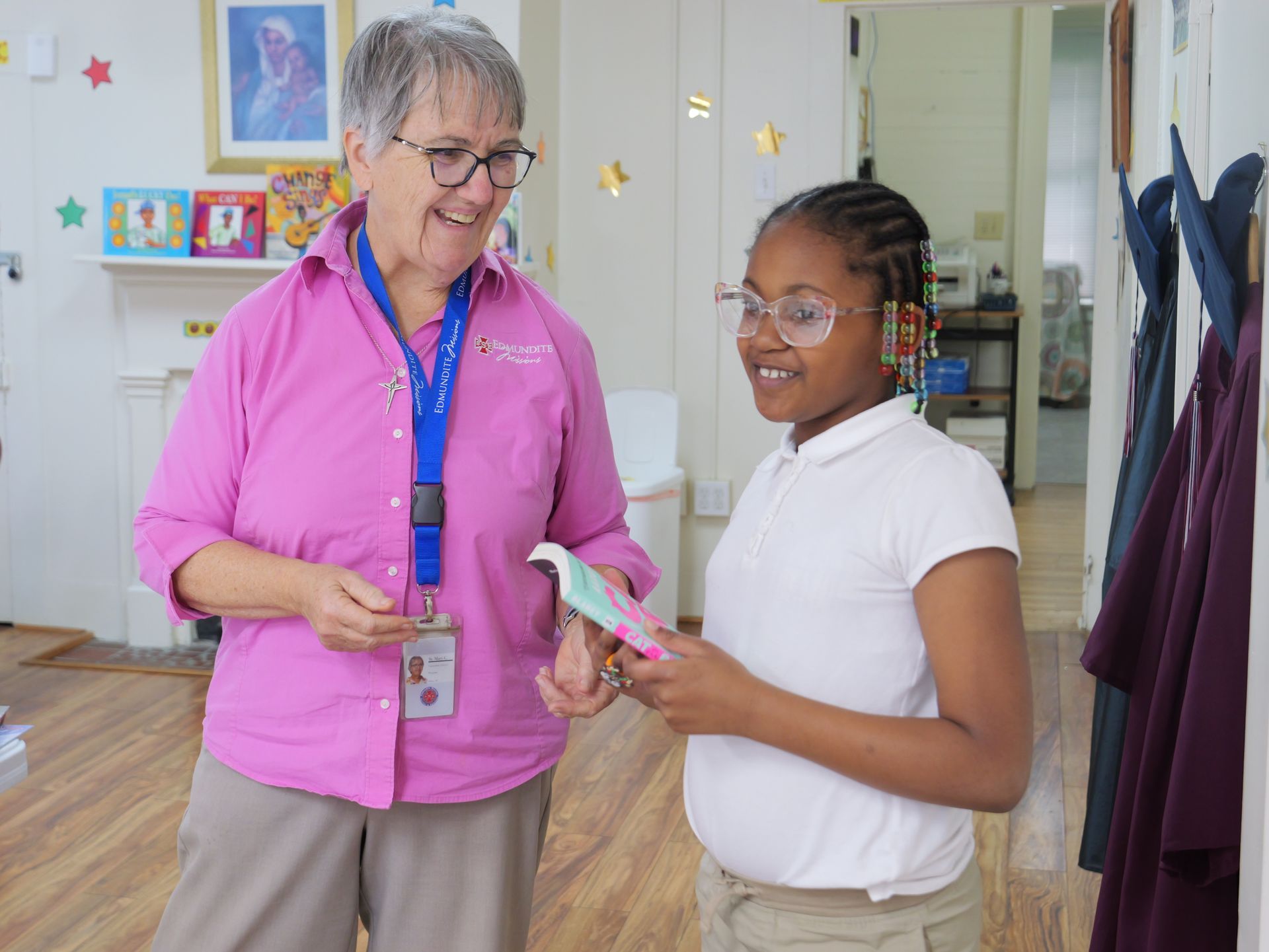 A woman in a pink shirt is talking to a young girl in a white shirt.