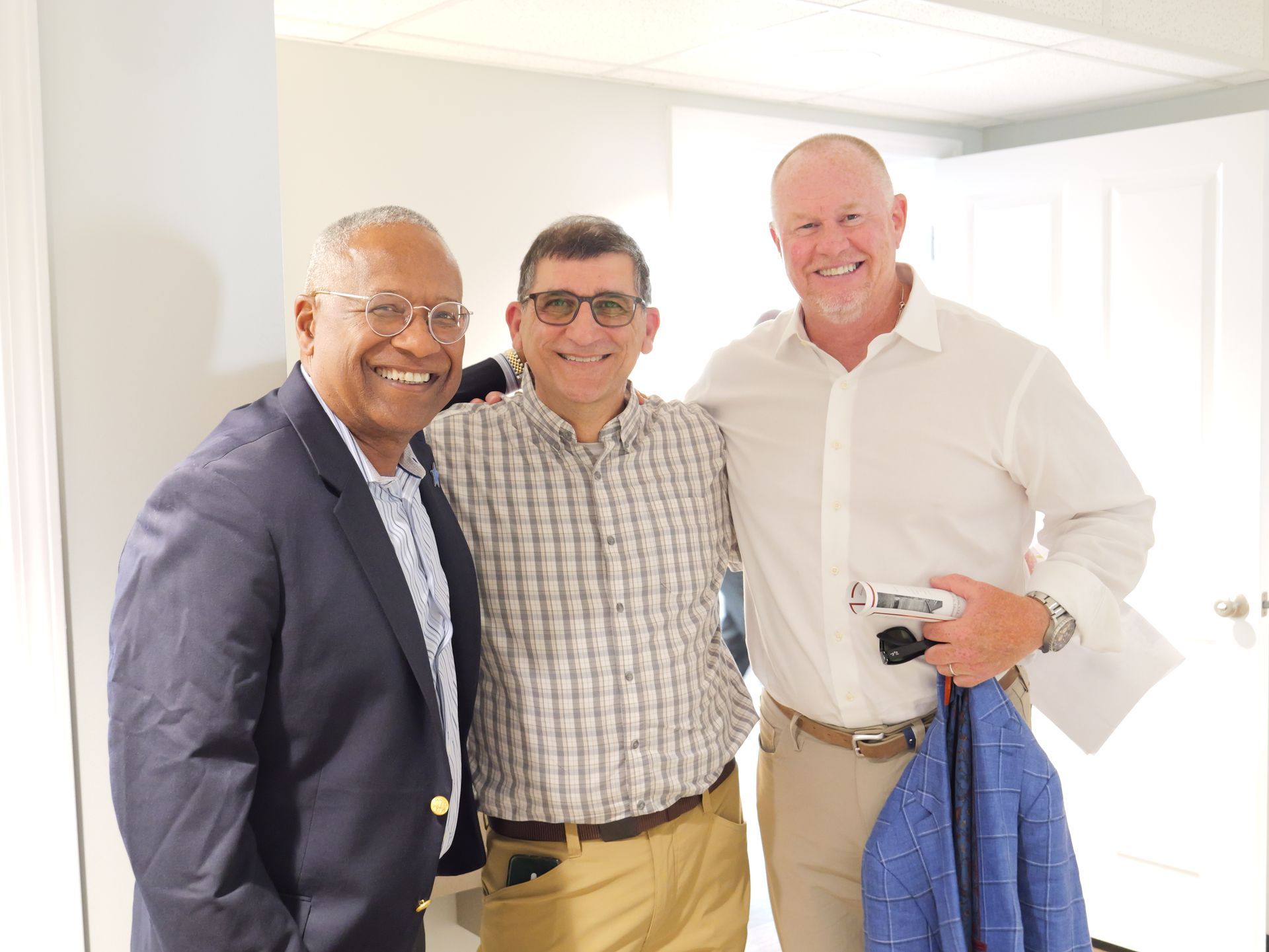 Three men are posing for a picture together and smiling for the camera.
