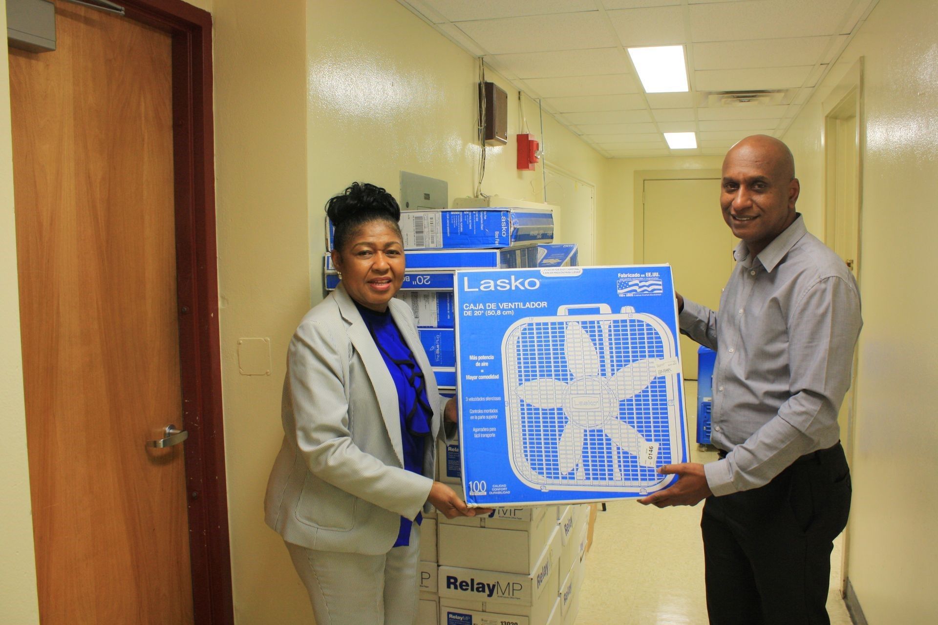 A man and a woman are holding a fan in a hallway.