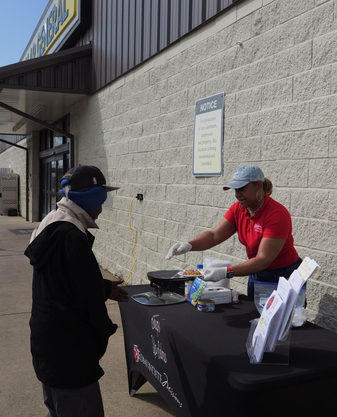 A woman in a red shirt is serving food to a man