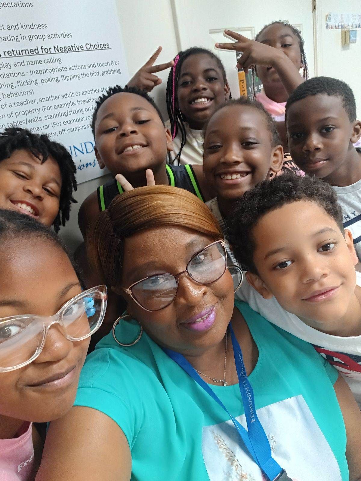 A group of children are posing for a picture with their teacher.