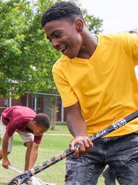 A boy in a yellow shirt is holding a hockey stick