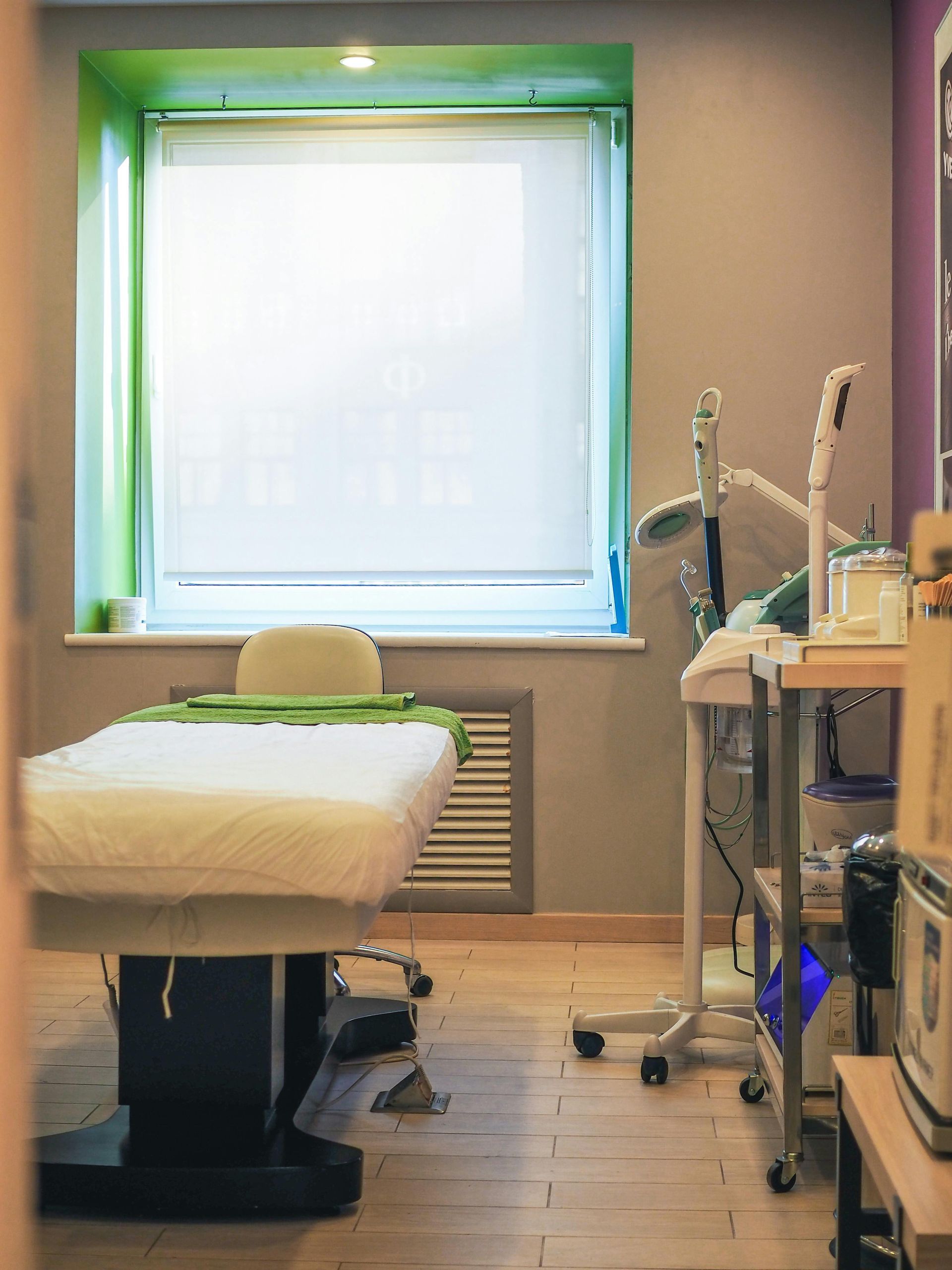 Treatment room with massage table, medical equipment, and window.