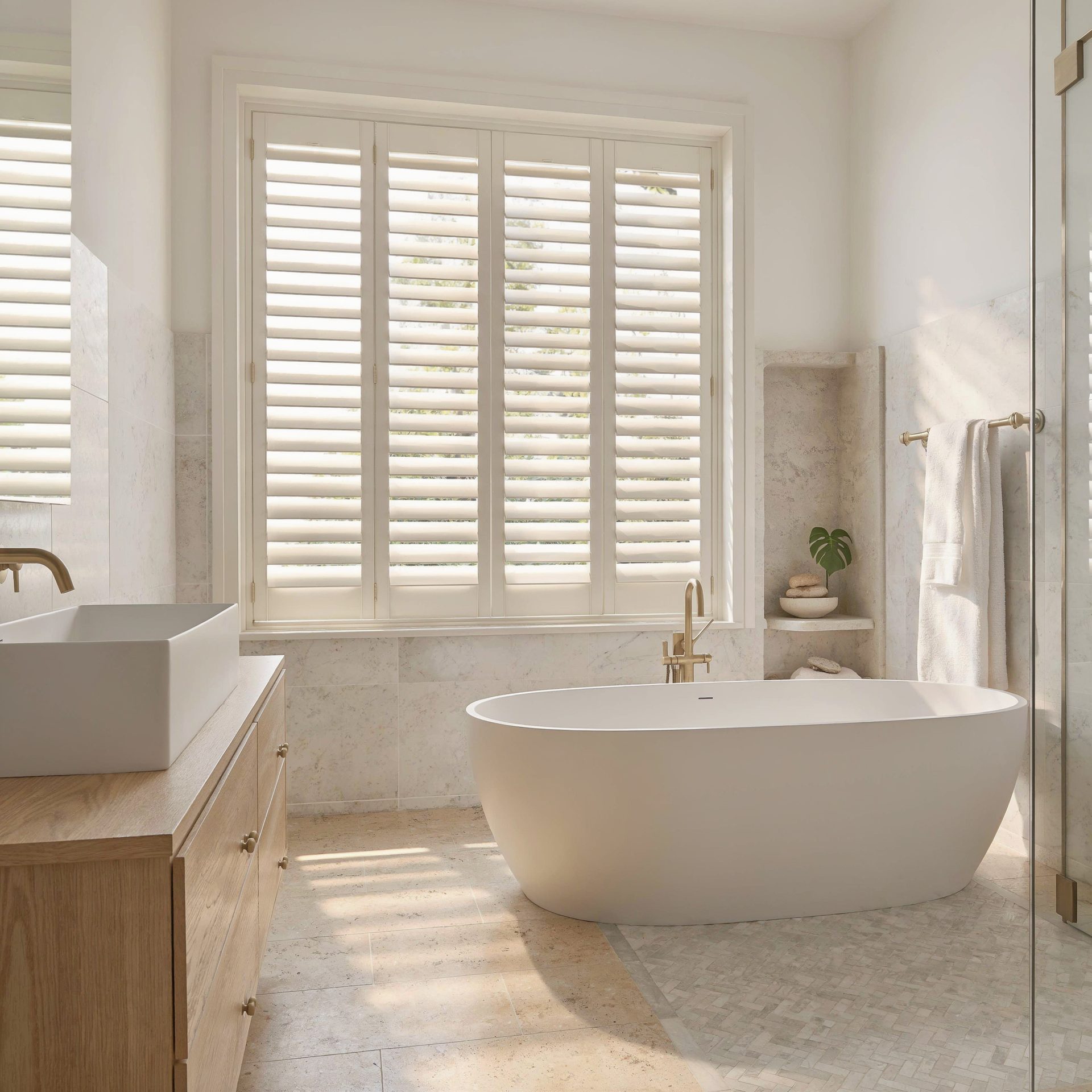 Bright modern bathroom with a freestanding tub, white shutters, and sunlight on the floor.