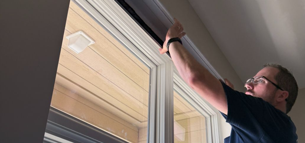 Sean Simmonds is installing window shades at a home.