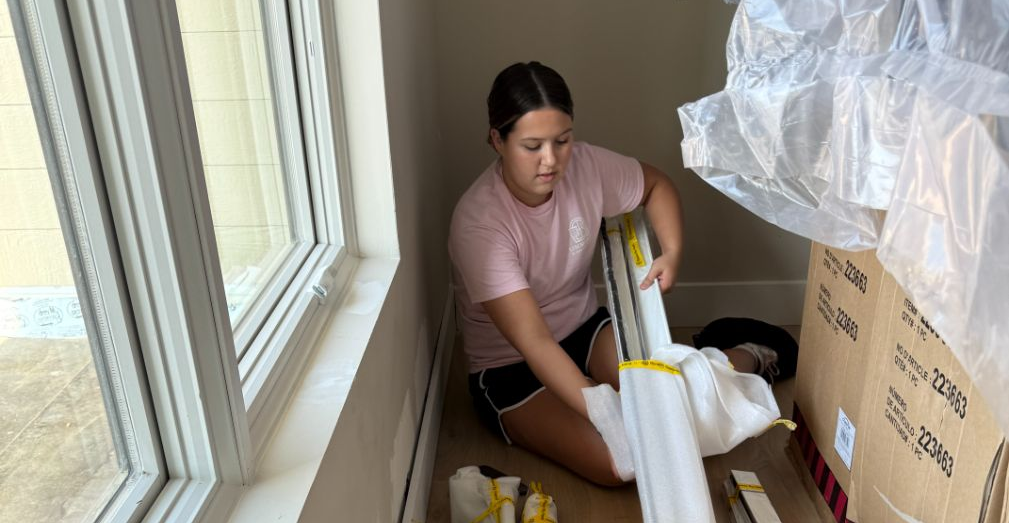 A Simmonds family member is unpacking boxes of window tratments for installation.