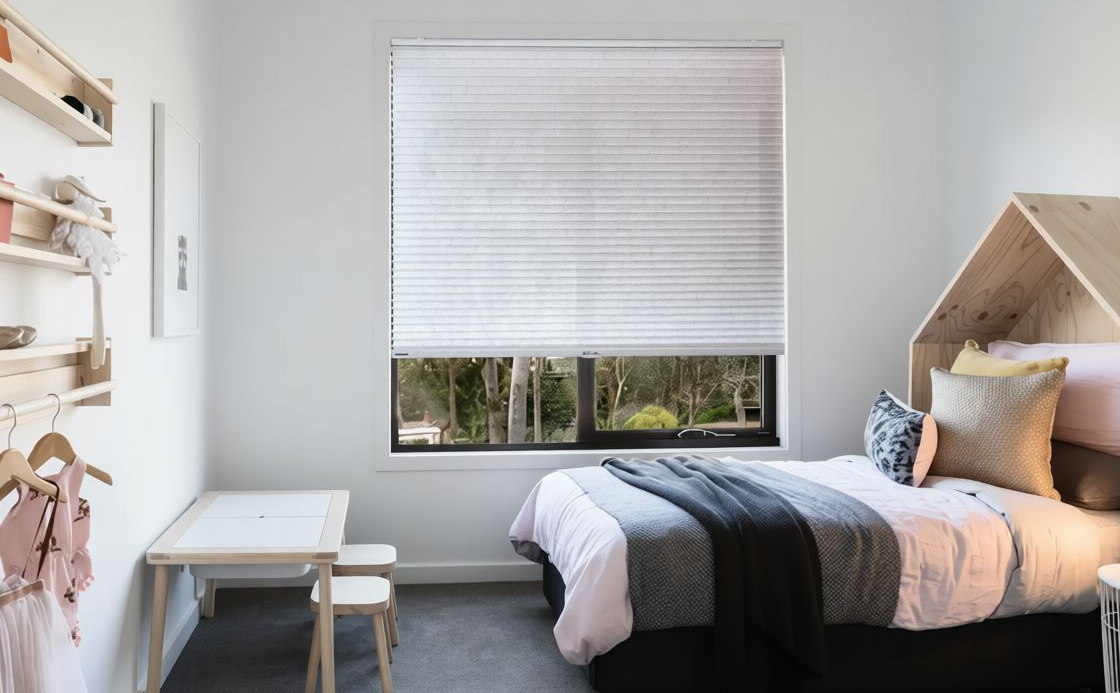Bedroom with bed, window with blinds, small table, and shelves with toys.