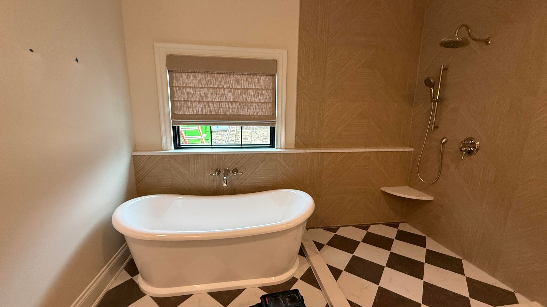 Bathroom with white clawfoot tub, diamond tile floor, tan walls, and a window with a shade.