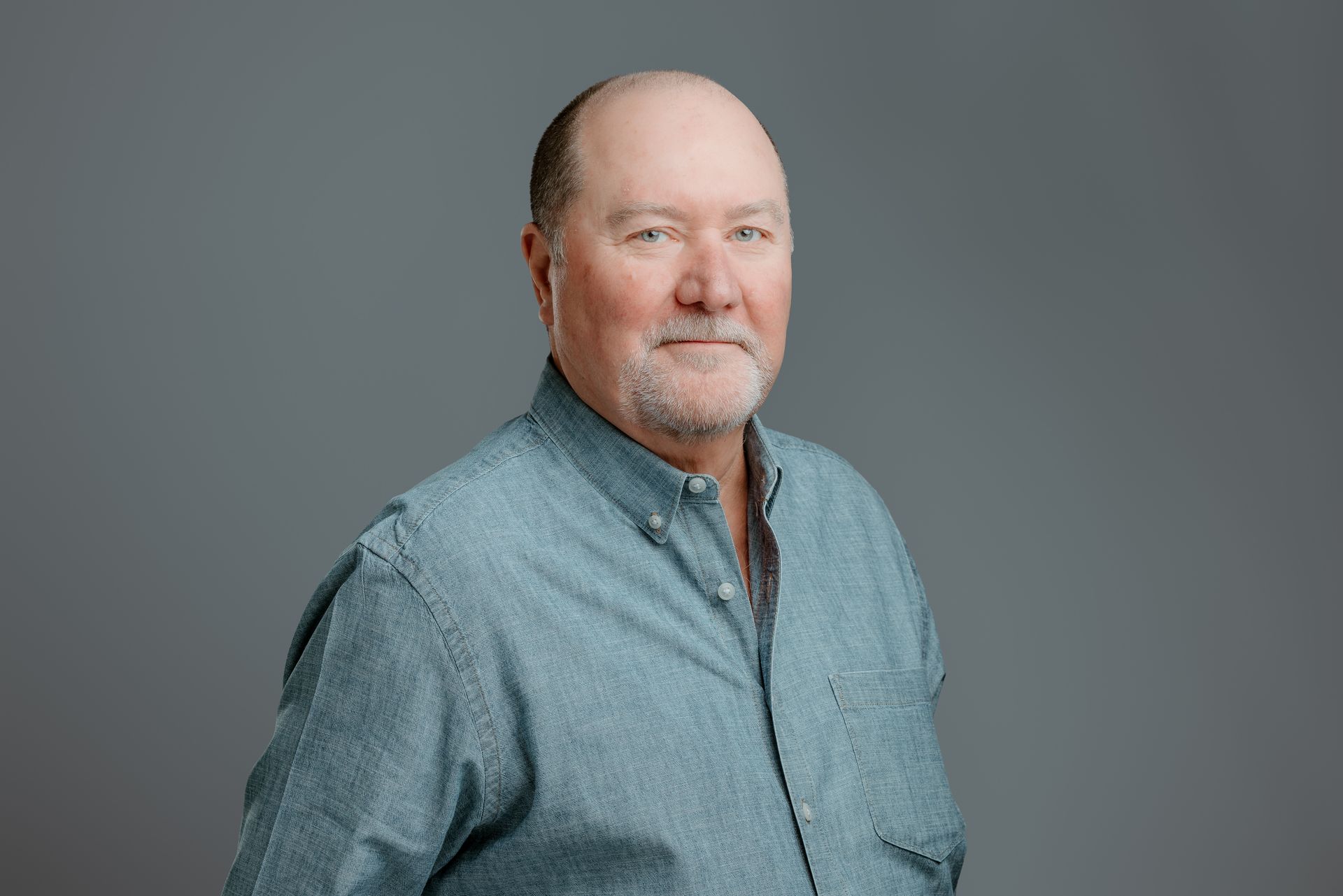 Smiling man in a gray cap and white shirt against a light background