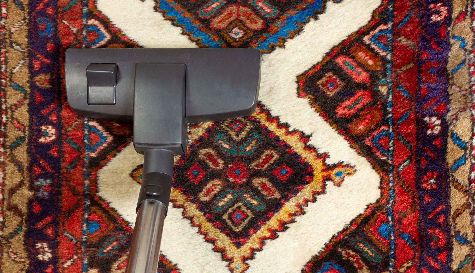 Vacuum cleaner head on a colorful patterned rug Vacuum cleaner head on a colorful patterned rug