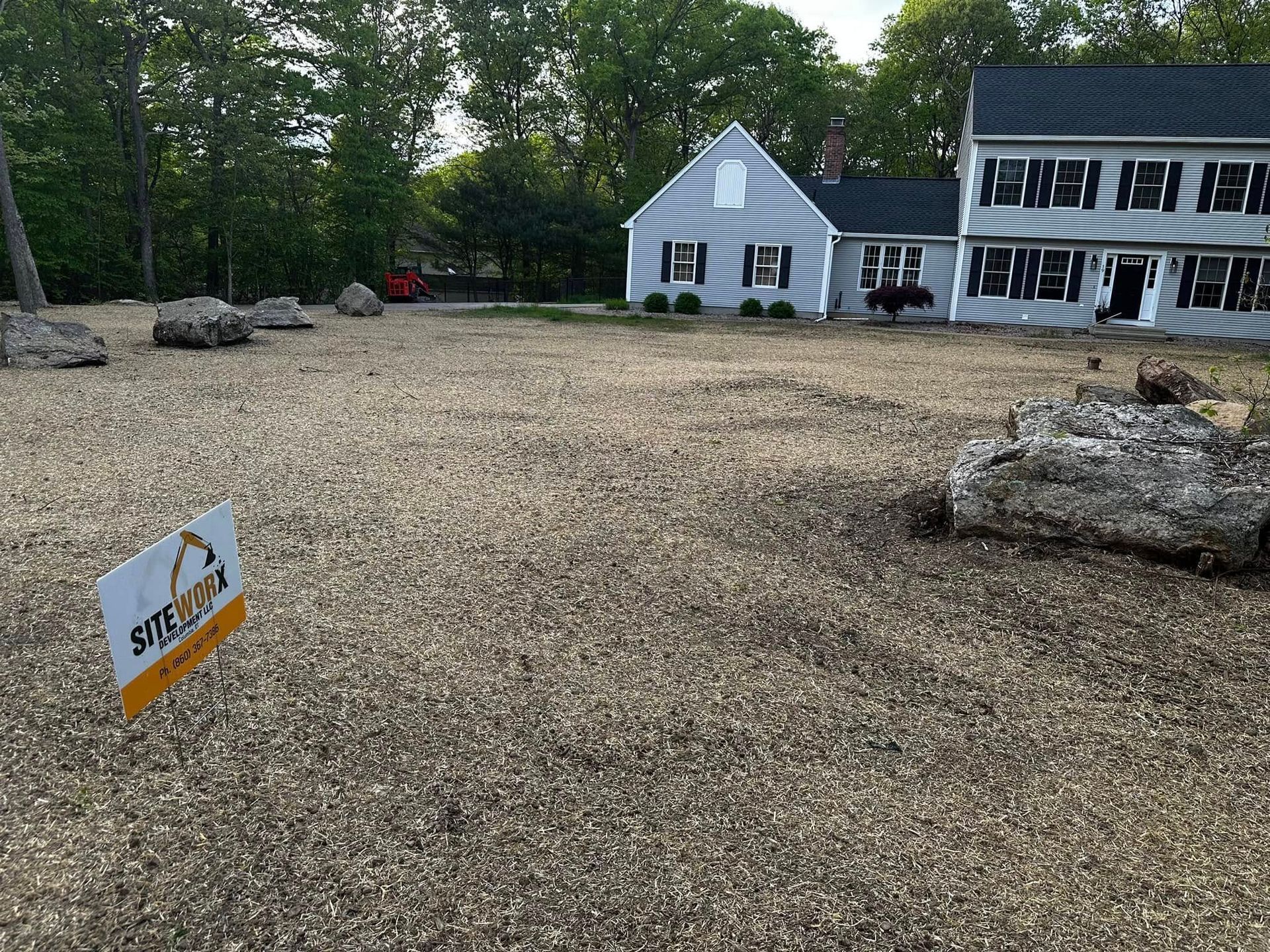 Gravel yard with large rocks, house in background, and a 