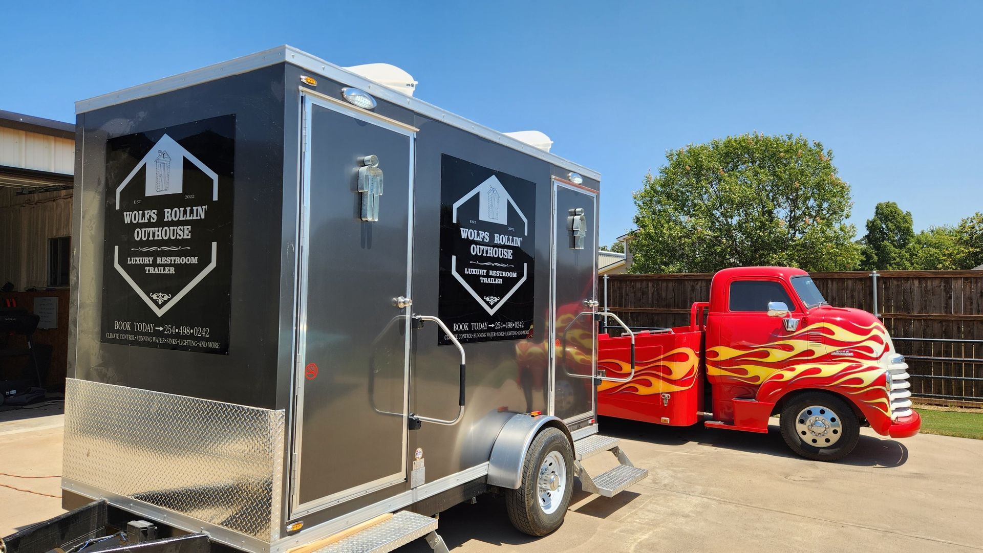 A red truck with flames on the side is parked next to a trailer.