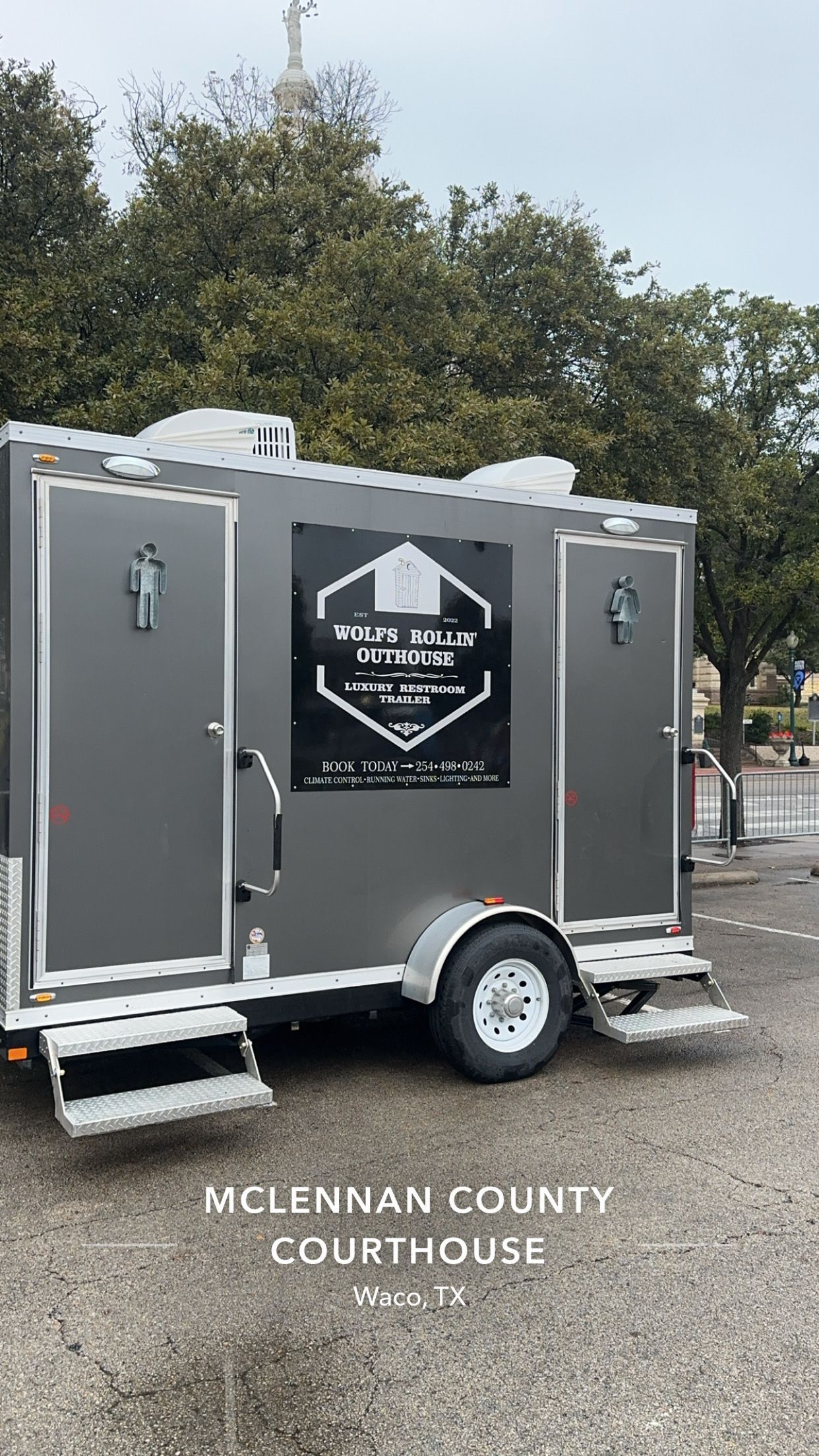 A trailer with two toilets on it is parked in a parking lot.