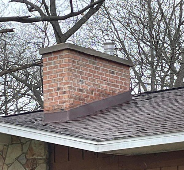 A brick chimney is on the roof of a house.