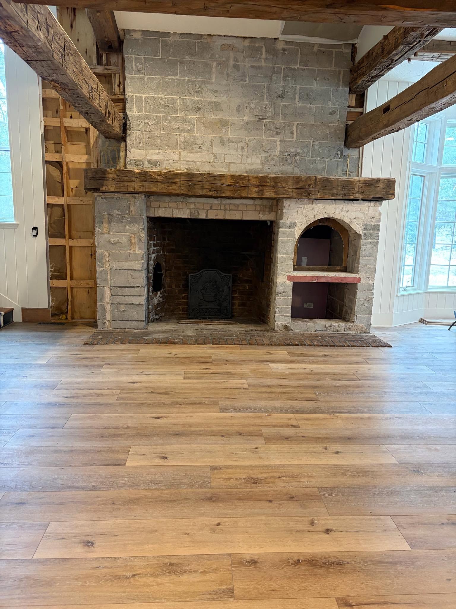 Stone fireplace in a rustic room with wood floors and exposed beams