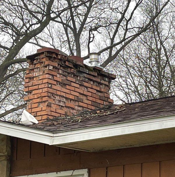 A brick chimney is on the roof of a house.