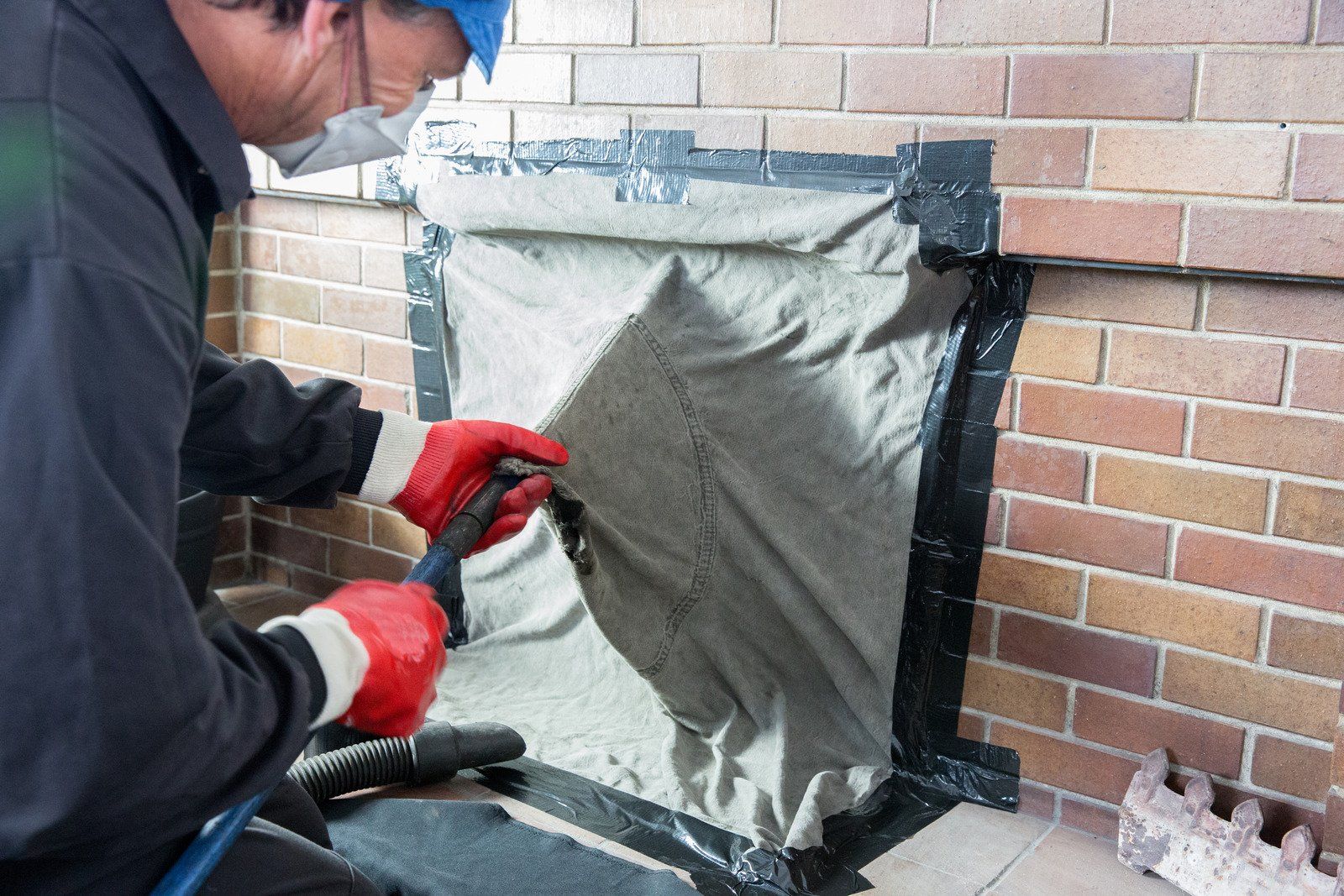 A man is cleaning a fireplace with a vacuum cleaner.