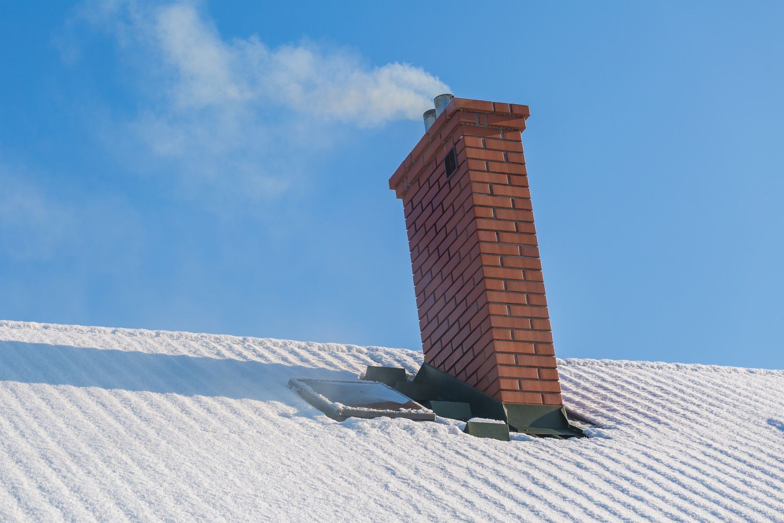 A brick chimney on top of a snow covered roof