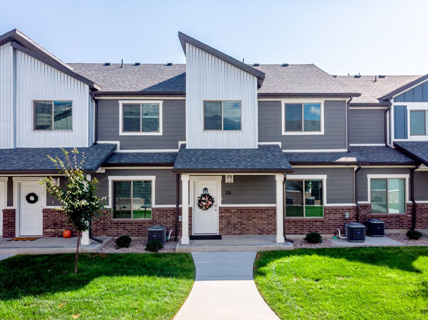 Exterior view of a modern townhouse-style apartment building with gray siding and a central walkway.