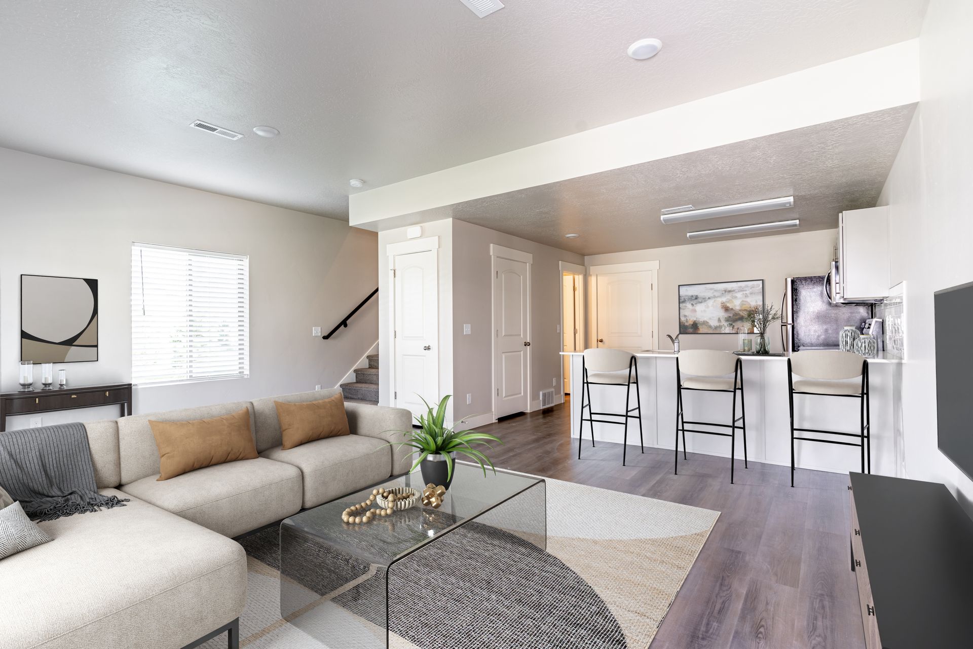 Modern open-concept living room and kitchen with gray sofa, white island, and wood flooring