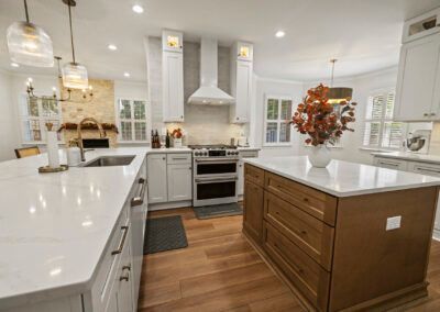 Bright white kitchen with island, wood floors, stainless range, and fall centerpiece on the counter