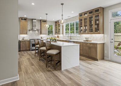 Modern kitchen with white island, wood cabinets, pendant lights, and large windows