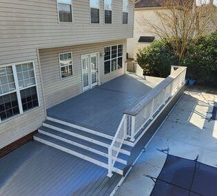 Back deck with gray stairs and white railings attached to a beige house