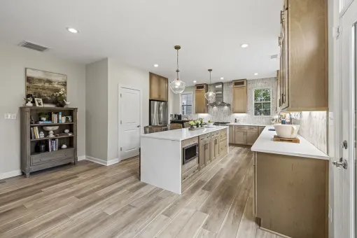Bright modern kitchen with white island, wood cabinets, and light wood flooring