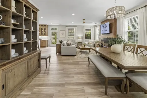 Bright open dining room and living area with wood furniture, chandelier, and large windows