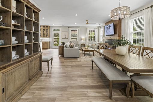 Bright open dining room and living area with wood furniture, chandelier, and large windows