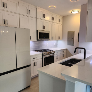 Bright white modern kitchen with island, black fixtures, stainless appliances, and built-in microwave