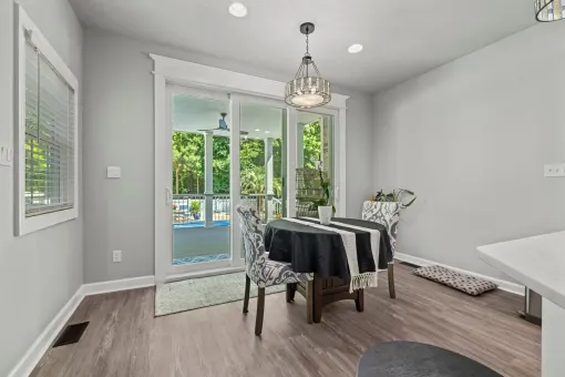 Bright dining room with table, chairs, chandelier, and sliding glass doors opening to a backyard pool.