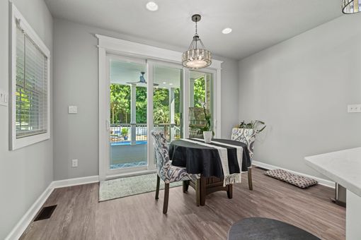 Bright dining room with table, chairs, chandelier, and sliding glass doors opening to a backyard pool.