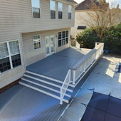 Back porch with gray deck, white railing, steps, and sliding glass doors on a house