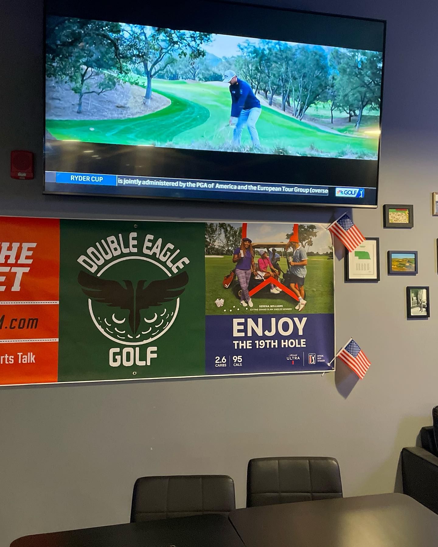 A large flat screen tv is hanging on a wall above a table and chairs.