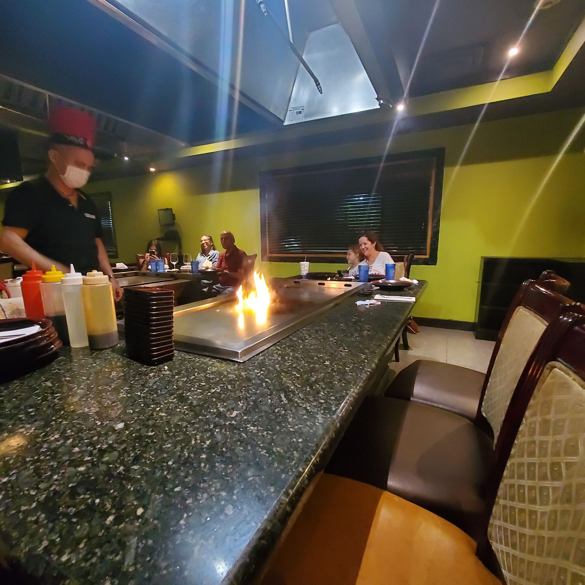 Restaurant teppanyaki grill with chef cooking over flames at a table for diners